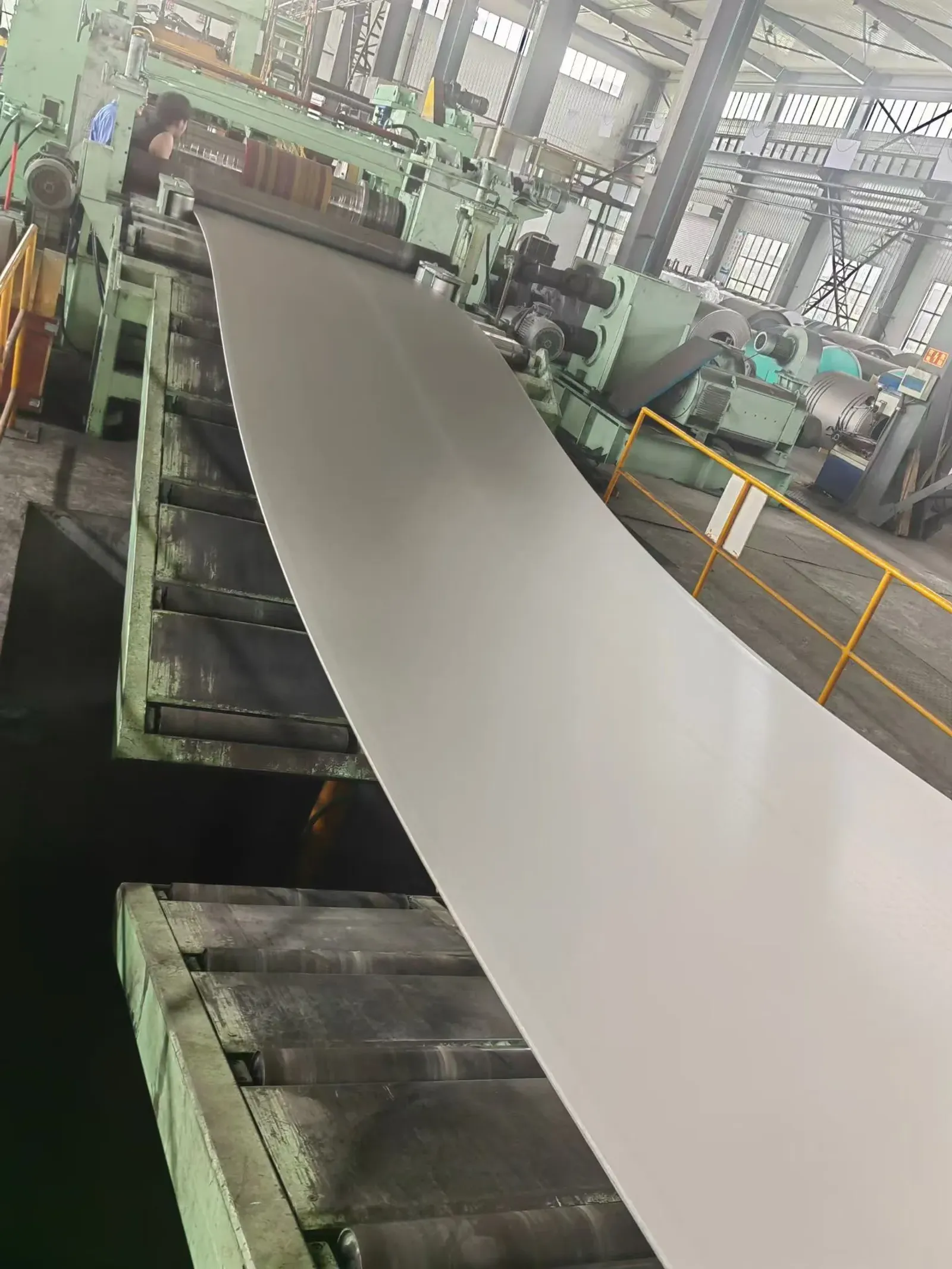 A user-supplied titanium sheet moving through a mill line illustrates real product-form processing; it is not a specimen from the cited impact study.
