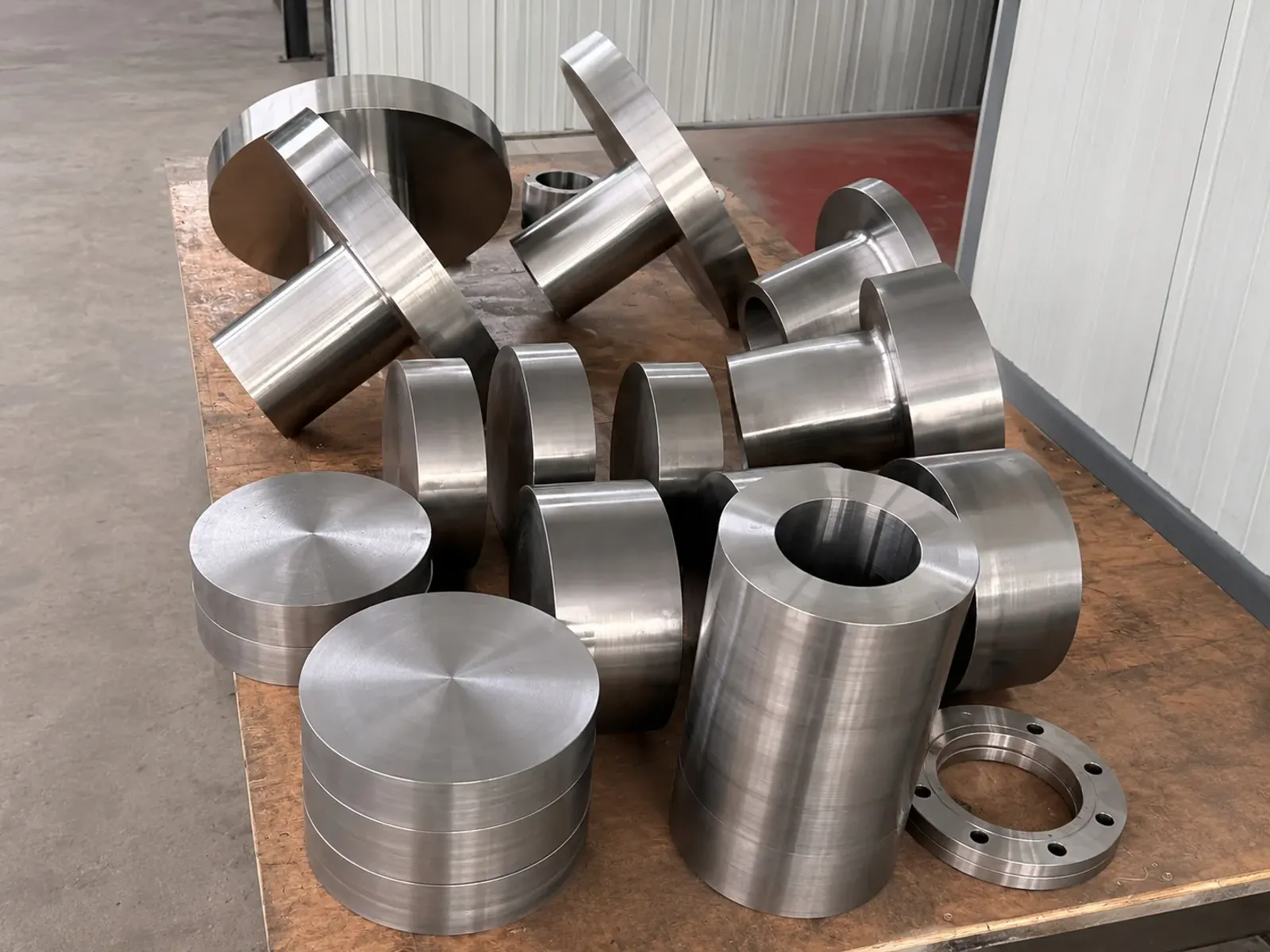 Machined cylindrical, ring and flange-shaped metal parts on a workshop table