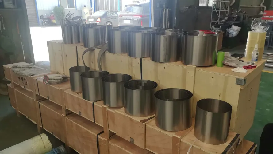 User-supplied cylindrical titanium products on shipping cases illustrate real hollow product geometry; they are not Ti65 rings or specimens from the cited study.