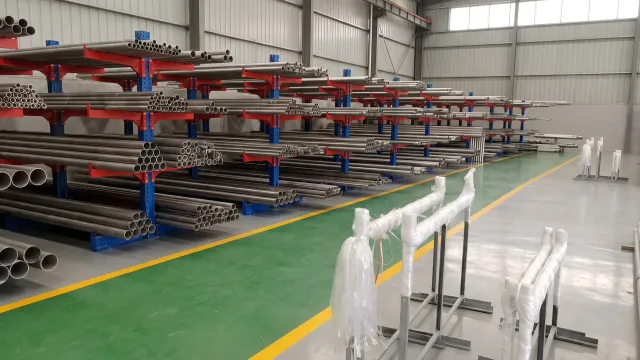 Titanium tubes and bars organized on cantilever racks along a wide high-bay warehouse aisle