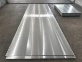 Großes gebürstetes Metallblech neben einem Stapel Blechmaterial