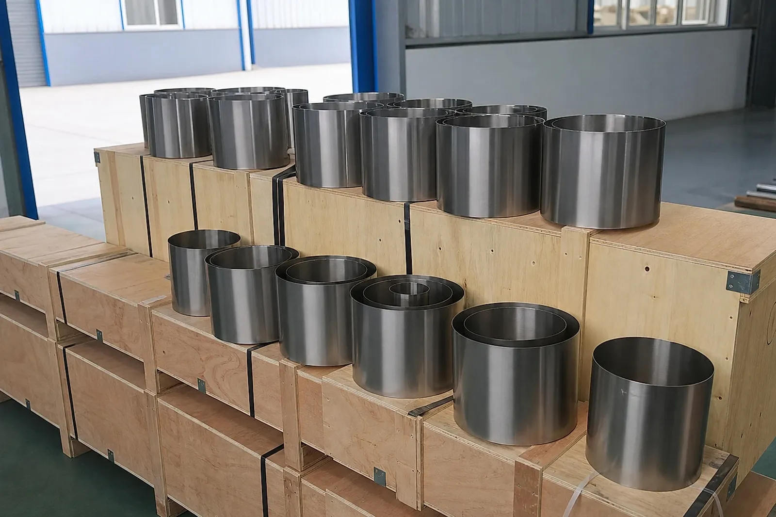 Piezas cilíndricas de titanio preparadas sobre cajas de exportación, mostrando por qué los compradores de AM necesitan identidad de lote y datos de liberación antes de aceptar el suministro.