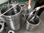 Trabajador comprobando anillos mecanizados similares al titanio con calibres, para mostrar que las piezas críticas necesitan evidencia dimensional, de proceso y de liberación antes del envío.