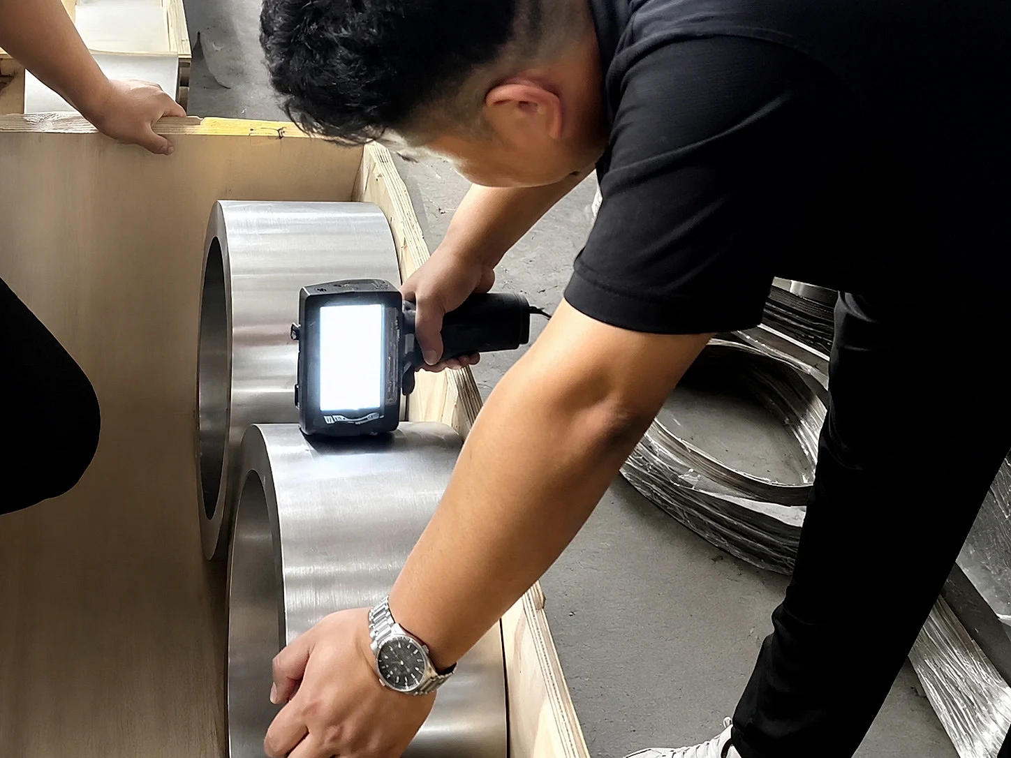 A handheld inspection device checks machined titanium-like ring stock, showing how source-control claims still need product-level verification before release