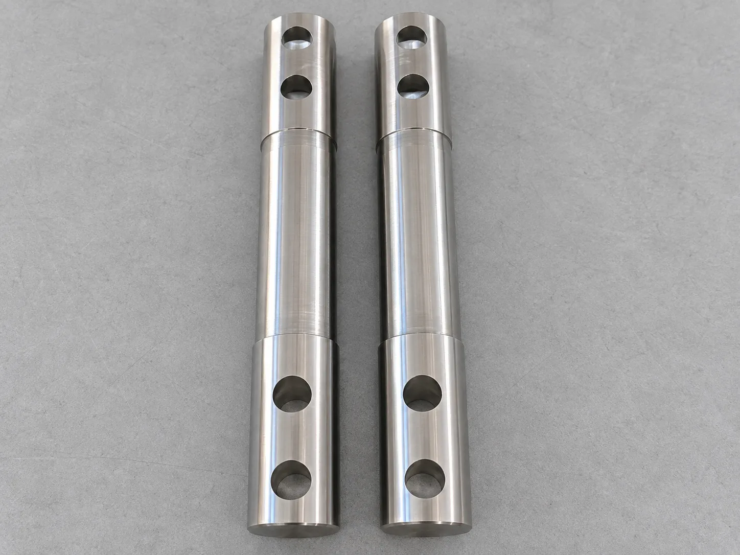 Two parallel machined cylindrical metal shafts with transverse holes