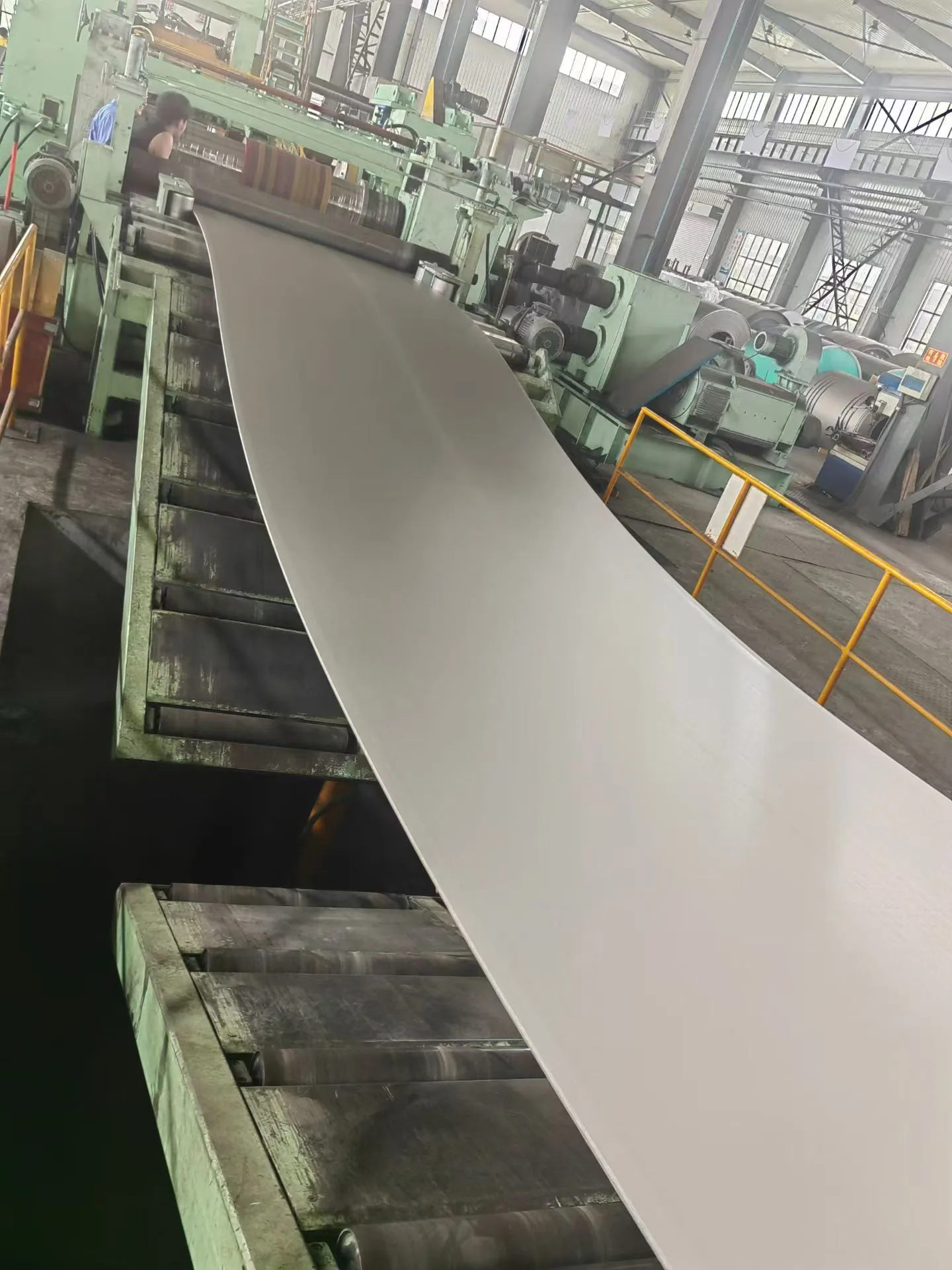 A user-supplied titanium sheet moving through a mill line illustrates real product-form processing; it is not a specimen from the cited impact study.