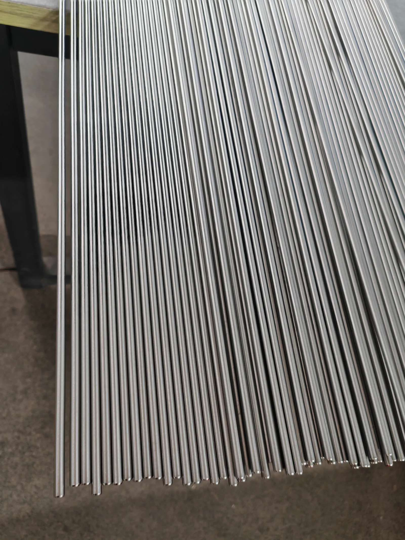 User-supplied small-diameter titanium rods illustrate controlled medical-material feedstock; they are not spinal cages or specimens from the cited review.