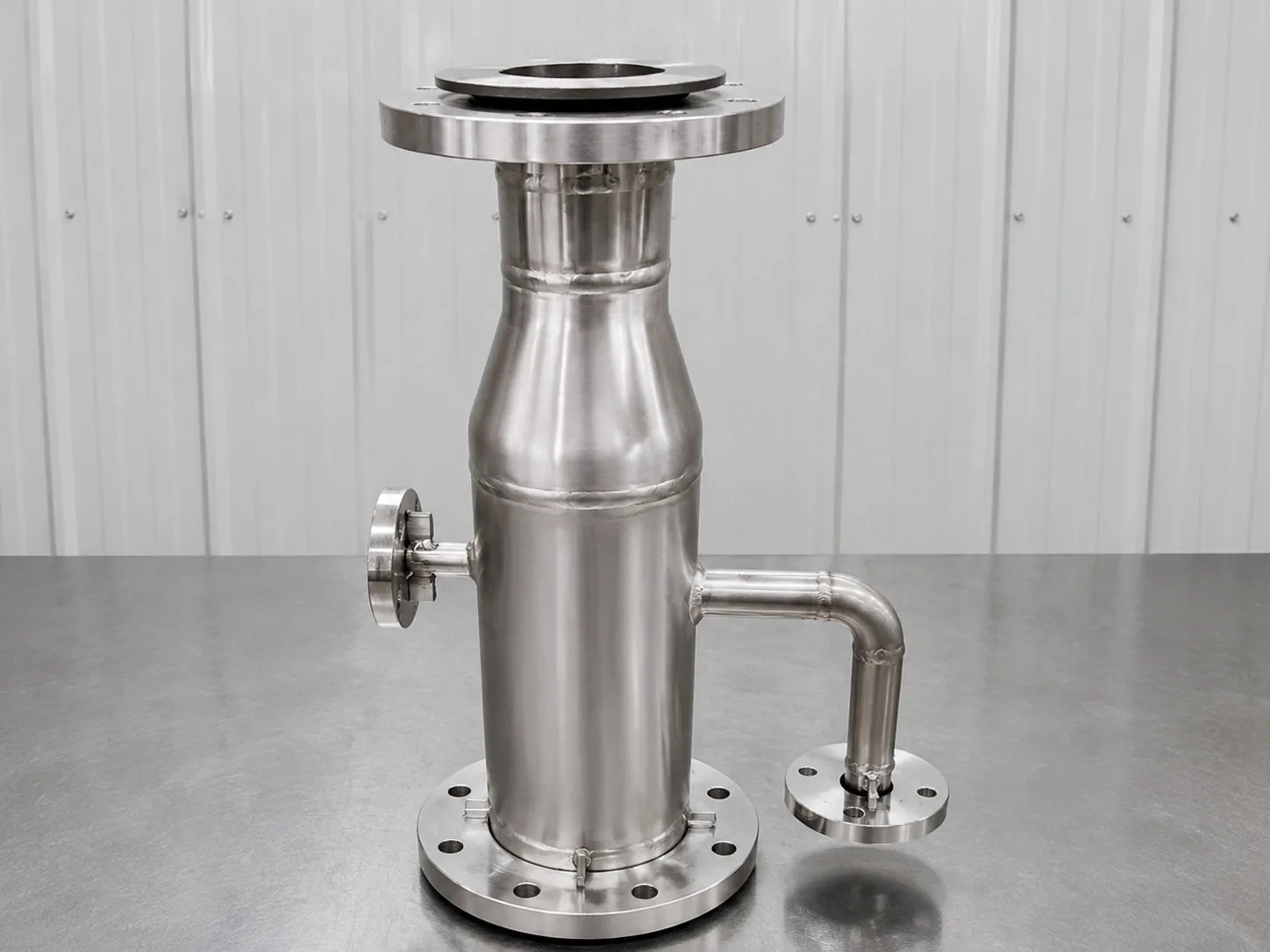 User-supplied flanged titanium process component with visible fabrication seams, illustrating why a finished geometry needs a stress-scale verification plan; it is not a specimen from the study.