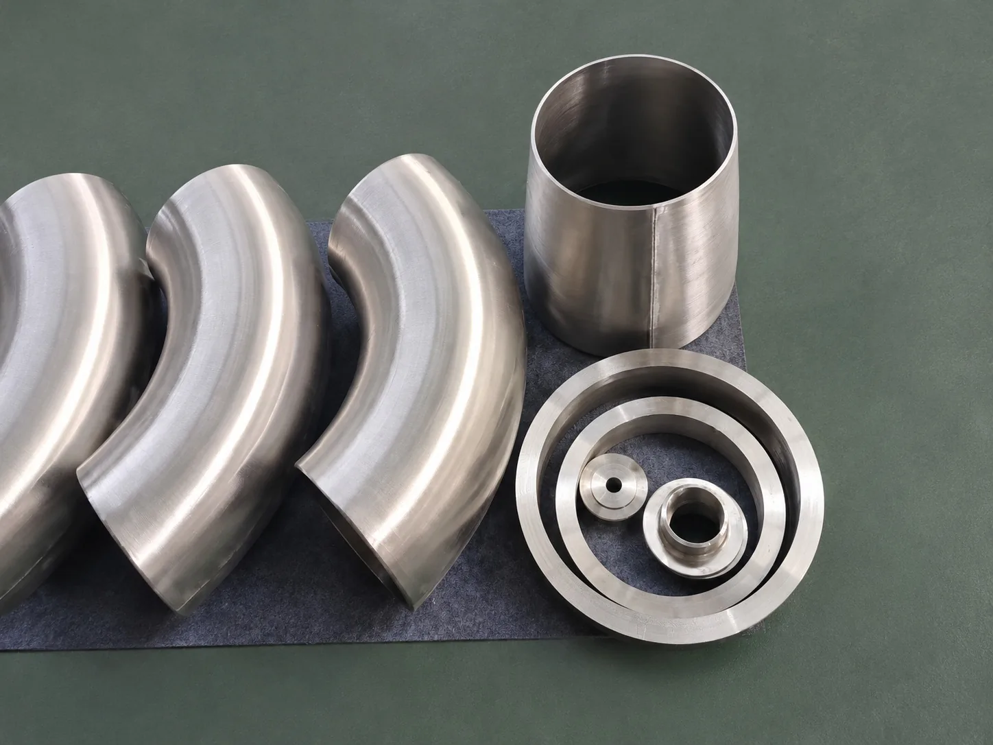 User-supplied titanium elbows and rings illustrate finished surface and geometry checks; they are not TiAl repair specimens or study evidence.