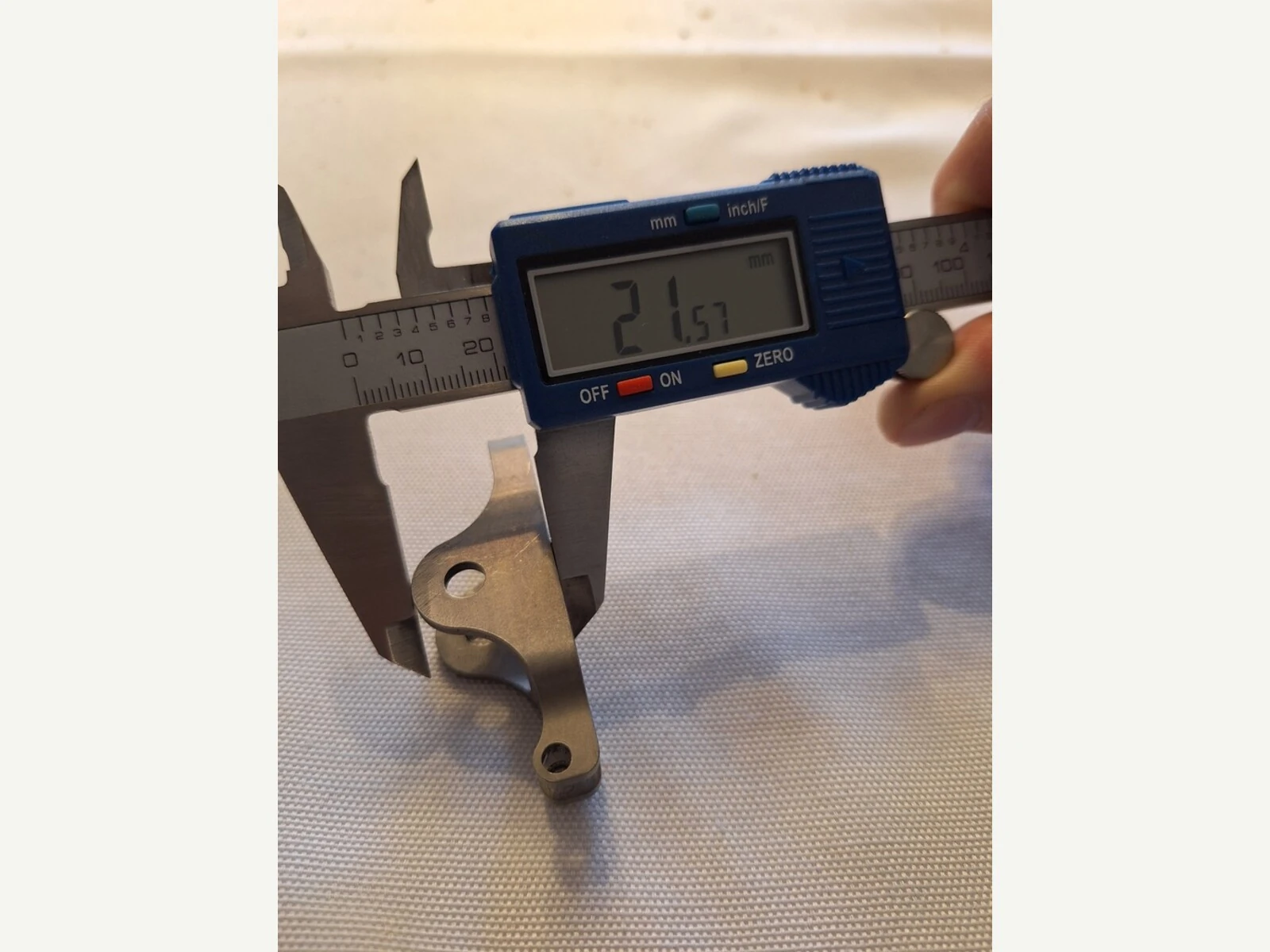 Digital caliper measurement of a small machined titanium part, showing why AM or machined routes still need dimensional verification in the buyer evidence file.