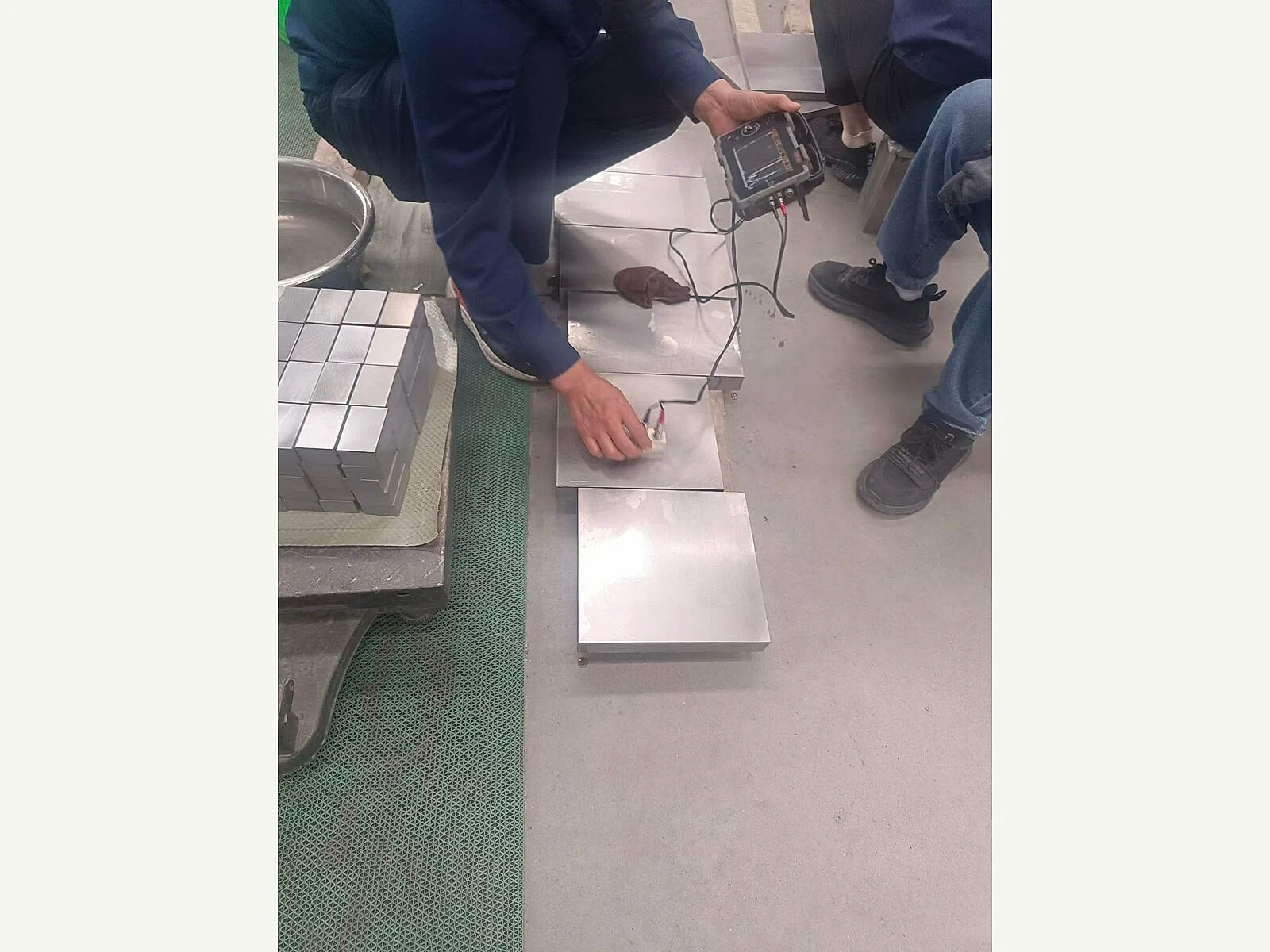 Prüfung von Titanplattenmustern mit einem Handgerät; sie zeigt die Verifizierungsebene, die Käufer vor der Annahme einer neuen Zusammensetzungsroute benötigen.