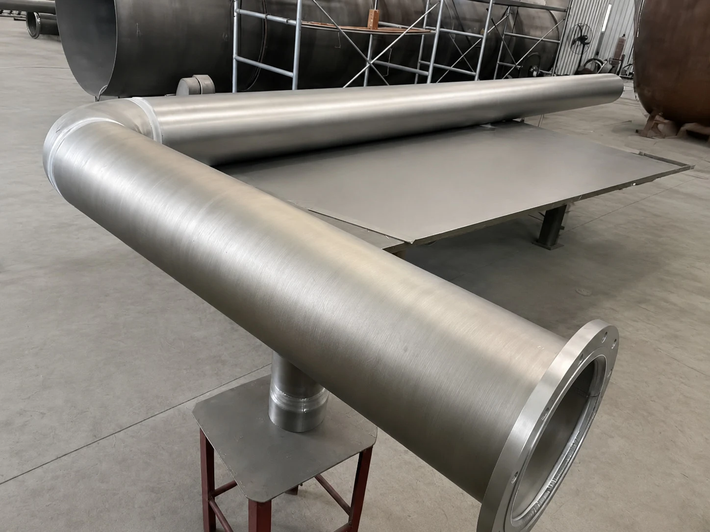 Large titanium pipe component in a workshop, illustrating how forged or machined product forms need route-specific inspection and release evidence.
