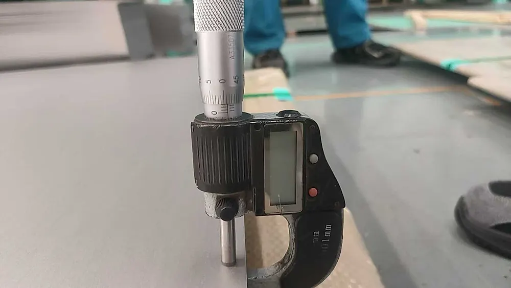 Digital micrometer measuring titanium plate thickness during quality inspection