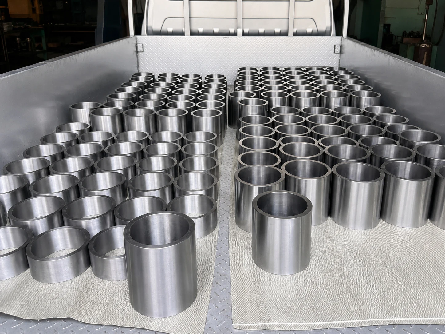 Repeated titanium-like sleeves staged for transport, illustrating lot repeatability and batch release control after component forming.