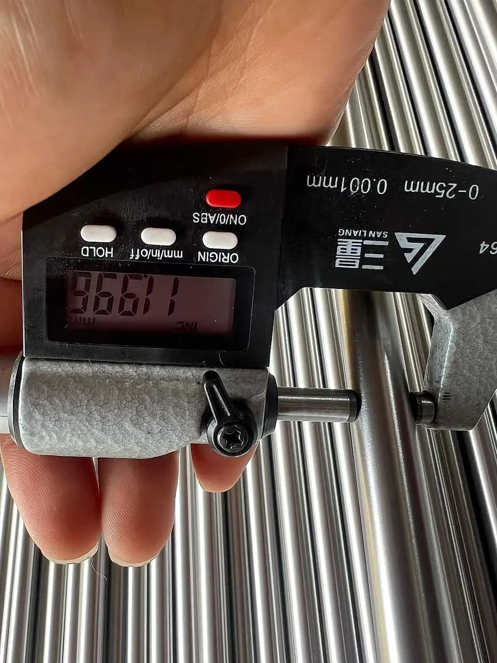 Micrometer measuring titanium rod diameter during quality check