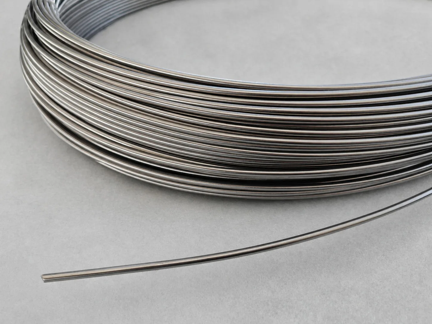 Coiled metal wire with a loose end on a neutral floor